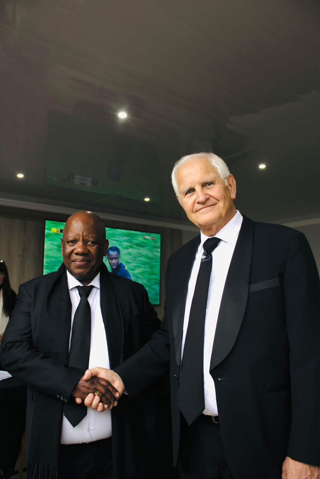 Two MUCM leaders shaking hands in formal attire